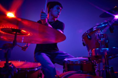 Gayri resmi giyinen davulcu. Stüdyonun arka planında pembe-mor sahne ışıklandırmasında ciddi bir ifade var. Müzik ve sanat kavramı, hobi, konserler ve festivaller, modern kültür. Ad