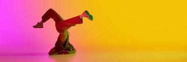 Pankart. Genç adam, break-dansçı baş üzerinde durur. Neon ışıkta, eğimli, pembe-sarı arka plana karşı. Metin eklemek için negatif alanı var. Hobi, spor, yaratıcılık, moda ve tarz kavramı. Ad
