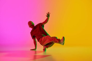 Genç, şık giyinmiş bir adamın dinamik fotoğrafı, neon ışıkta, arka plandaki pembe renge karşı performans sergiliyor. Sanat, hobi, spor, yaratıcılık, moda ve tarz, eylem kavramı. Ad