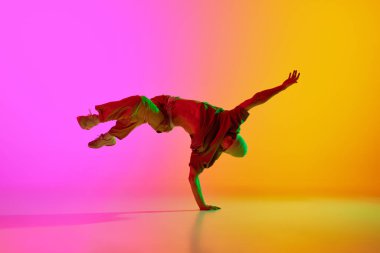 Talented young man dancing in hip-hop style, performing in neon light against gradient pink-yellow background. Concept of art, hobby, sport, creativity, fashion and style, action. Ad clipart