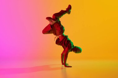 Havalı tavır genç, sanatsal adam neon ışıkta hareket ederek arka plandaki pembe renge karşı break dans yapıyor. Sanat, hobi, spor, yaratıcılık, moda ve tarz, eylem kavramı. Ad