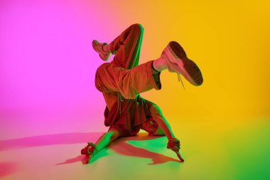 Hareketlerle kendini ifade etmek. Neon ışıklarıyla dans eden çağdaş dansçı, eğimli pembe-sarı arka plana karşı. Sanat, hobi, spor, yaratıcılık, moda ve tarz, eylem kavramı. Ad