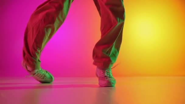 穿着运动服的男舞者在霓虹灯下在渐变的粉色和黄色背景下表演霹雳舞 业余爱好 时尚和风格 行动的概念 — 图库视频影像
