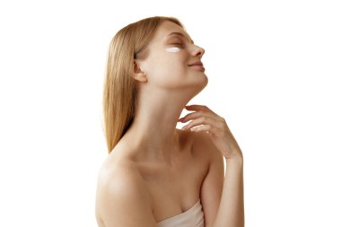 Yanaklarında canlandırıcı krem örnekleri olan genç ve hassas bir kadının portresi beyaz stüdyo arka planına karşı. Doğal güzellik kavramı, organik kozmetik, spa prosedürleri, yüz bakımı.