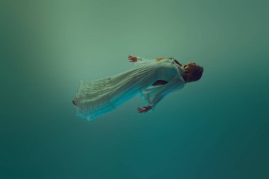 Dinamik poziyondaki genç bir kadın, su ortamında düşerken elbisesi çok güzel görünüyor. Güzellik kavramı, zarafet, gizem ve derinlik, ağırlıksızlık. Ad