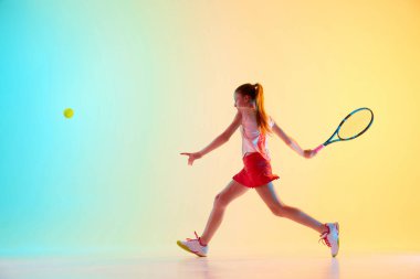 Genç kızın dinamik çekimi, tenis sporcusu, mavi-sarı arka planda neon ışığı altında sıkı bir ön saha tekniği eğitiyor. Bireysel spor, moda, turnuva kavramı. Ad
