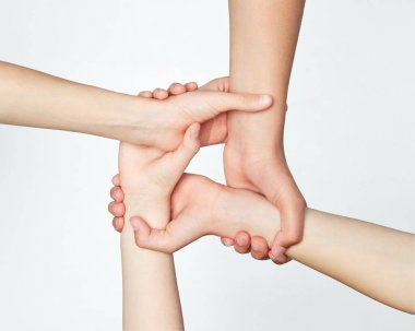 Bir grup çocuk el ele tutuşuyor, takım çalışmasını sembolize ediyor ve gri arka plana karşı destek veriyor. Gençlik kavramı, ifade, güzellik, duygular, jestler, sanat ve sembolizm, birlik Ad