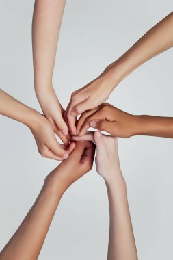 İnsan elinden yapılmış spiral, gri arka planda farklı ırktan çocukların kolları. Sadakat ve birlik. Gençlik, ifade, güzellik, duygular, jestler, sanat ve sembolizm kavramı, çeşitlilik. Ad