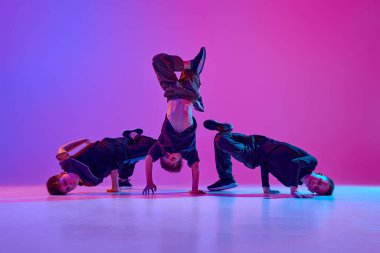 Genç çocukların enerjik bir fotoğrafı, siyah giyinmiş, hareketli hip-hop dansı yapıyor karışık neo-n ışığı altında, değişken arka planda. Spor ve hobi kavramı, müzik, moda ve sanat, hareket. Ad