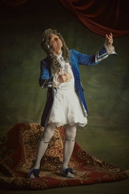 Oldukça detaylı barok bir kostüm giymiş kulaklıkla müzik dinleyen aşırı neşeli bir adam klasik stüdyo geçmişine karşı. Dönem karşılaştırmaları kavramı, modernlik ve tarihin birleşimi, teknoloji.