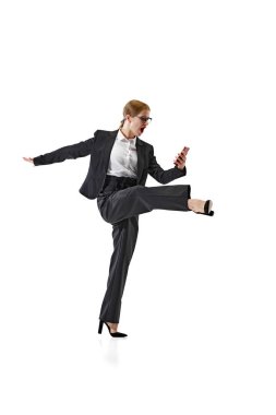 Siyah takım elbiseli iş kadını telefonunu beyaz stüdyo geçmişiyle karşılaştırırken şaşırdı. Beklenmedik haberler. İş, iş ve öğrenim kavramı, hobi, serbest meslek, ofis. Ad