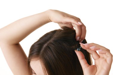 İpeksi, düz saçlı, beyaz arka planda yağlı kapsülü tutan genç esmer kadınlara yakın durun. Saç tedavisi, hijyen, spa prosedürleri, sağlık. Ad