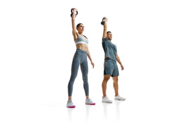 Kettlebell basın egzersizi yapan kadın ve erkek eğitimine odaklanmış ve beyaz stüdyo geçmişine karşı mükemmel bir form sergilemiştir. Spor, sağlıklı yaşam tarzı, takım çalışması kavramı. Ad