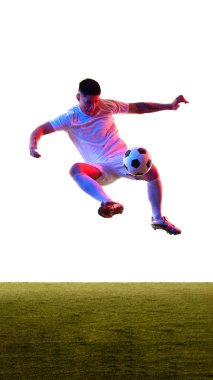 Spor kıyafetleri giymiş genç adamın neon ışıkta topu beyaz stüdyo arka planına fırlatmak için havaya sıçramasının dinamik görüntüsü. Profesyonel spor, rekabet, turnuva, enerji, aksiyon kavramı. Ad