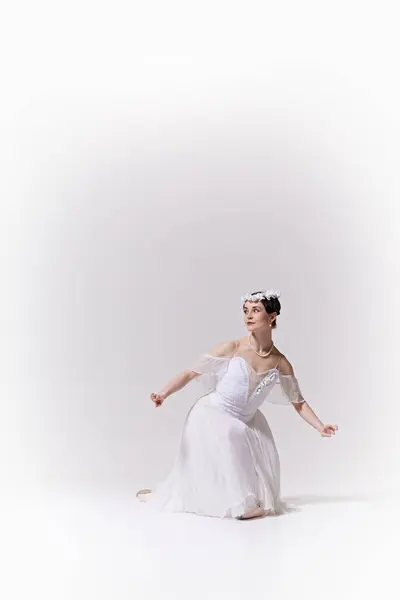 stock image Poster. Ballerinas white gown and floral headpiece accentuate her ethereal presence against white studio background. Concept of art, fusion of classic and modernity, grace and elegance.