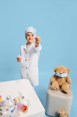 Hekimlik heveslisi. Beyaz önlüklü ve şapkalı bir çocuk, tıbbi aletler ve oyuncak ayılarla çevrili, gelecekte sağlık sektöründe kariyer yapmayı hayal ediyor. Çocukların hayalleri, gelecekteki kariyerleri, meslekleri, oyunları, fantezileri