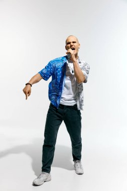 Yetenekli kel adam, rapçi, vokalist mikrofona şarkı söyleyen beyaz stüdyo arka planına karşı hareket eden. Müzik anlayışı, festivaller, çağdaş sanat, hobi, yaratıcılık. Ad