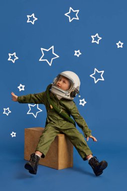 Geleceği hayal et, çocuk, pilot kıyafetli küçük çocuk ahşap kutunun üzerinde oturuyor, kolları açık mavi arka planda yıldızlarla çevrili. Çocuk hayalleri, gelecekteki kariyer, oyunlar, fantezi. Ad