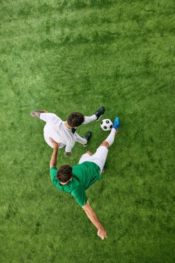 Hava görüntüsü. Sahada futbol oynayan iki genç sporcu. Yeşil yemyeşil çocuk parkındaki futbolcular. Profesyonel spor konsepti, şampiyonluk, final maçı, hareket. Ad