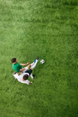 Hava görüntüsü. İki oyuncu yeşil yemyeşil oyun alanında top için yarışıyor. Futbol maçında gergin bir an. Profesyonel spor konsepti, şampiyonluk, final maçı, hareket. Ad
