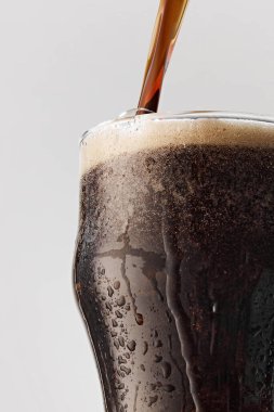 Sıcak, karanlık, bira kadehinin içine dökülüyor ve cam üzerinde gri stüdyo arka planına yoğunlaşıyor. Yiyecek ve içecek kavramı, kutlama, Ekim festivali, içecek endüstrisi. Ad