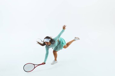 Turkuaz kıyafetli tenisçi, forehand swing yapıyor, çevikliğini ve gücünü beyaz stüdyo arka planına karşı gösteriyor. Profesyonel spor konsepti, şampiyonluk, aktif yaşam tarzı, turnuva.