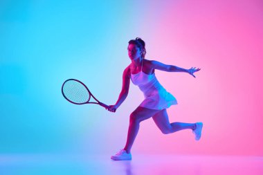 Atletik kadın, beyaz kıyafetli tenisçi canlı gradyan stüdyo arka planına karşı neon ışıkta sallanırken yakalandı. Profesyonel spor konsepti, şampiyonluk, aktif yaşam tarzı, turnuva. Ad