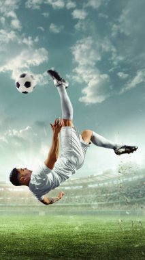 Dikey oryantasyon. Futbolcu, taraftarlarla dolu sahnelerle stadyumda arka planda muhteşem bir tepe vuruşu sergiliyor. Spor oyunları konsepti, yarışma, şampiyonluk, turnuva. Ad