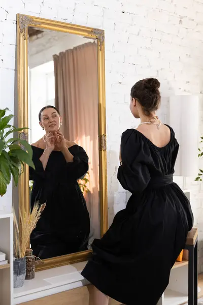 stock image Portrait of young attractive woman looks at mirror with reflection of beautiful mature woman, blending present and future selves. Concept of past and future, generation, memories, female beauty.