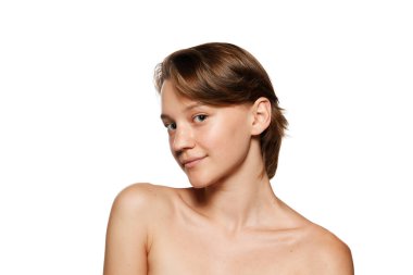 Çıplak omuzlu, beyaz stüdyo arka planına gülümseyen, kameraya bakan doğal güzel bir kadın. Yumuşak ciltli bir model. Gençlik, güzellik ve moda kavramı, kozmetik ürünü, dermatoloji