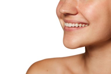 Diş beyazlatma. Beyaz dişlerini ön plana çıkaran ve beyaz stüdyo arka planında kayak yapan kadınların yakın plan çekimleri. Gençlik kavramı, güzellik ve moda, kozmetik ürünler, dermatoloji. Ad