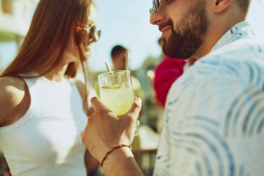 Dostlar bir araya gelip kadeh kaldırırken kahkaha ve neşe doludur. İçkileri güneş ışığında ışıldarken. Dışarıdaki bir grup insan. Parti anlayışı, Cuma havası, kutlama, yaz tatili, rahatlama.