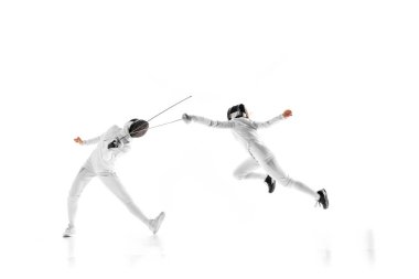 İki kadın eskrim sporcusu antrenman yapıyor, beyaz stüdyo arka planında hareket halindeki ayak hakimiyetlerini geliştiriyorlar. Profesyonel spor, rekabet, eylem kavramı. Ad