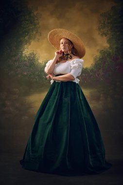 Orta çağ giysileri, elbise ve hasır şapka giymiş zarif genç bir kadının klasik arka planda güvenle poz verdiği tam boy portresi. Sonsuz güzellik. Tarih kavramı, çağların karşılaştırması, moda