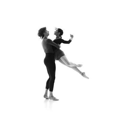 İkili zarif bale eğitimi seansı. Beyaz stüdyo arka planına odaklanmış ve hazır dansçılar hareket halinde. Siyah beyaz filtre. Çift eğitimi, klasik bale, güzellik, yaratıcılık kavramı. Ad.
