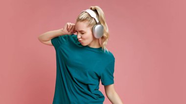 Genç bir kadın kulaklıkla müzik dinlerken ve Pastel Pembe Stüdyo 'nun arka planında şarkı söylerken mutluluk saçıyor. Boş zaman kavramı, olumlu duygular, kaygısız, neşe ve eğlence. Ad