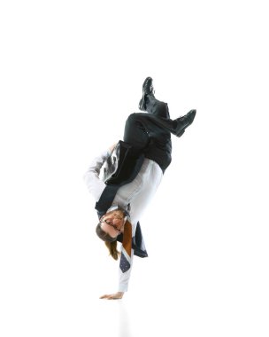 Profesyonel, resmi giyinmiş, dinamik amuda kalkıyor, enerji elementlerini birleştiriyor, beyaz stüdyo arka planına karşı esneklik gösteriyor. İş anlayışı, modern çalışma kültürü, moda. Ad