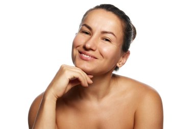 Çekici, güler yüzlü, cildine iyi bakılmış bir kadın eline yaslanmış ve beyaz stüdyo arka planına doğru kameraya bakıyor. Görünüş ve özgüven. Yüz bakımı, kaldırma, ameliyat kavramı.