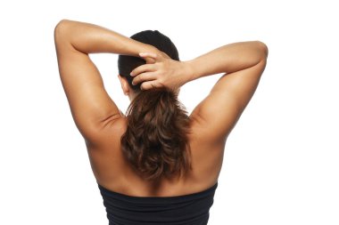 Arkadan gösterilen kadın, uzun, dalgalı, doğal saçlarıyla beyaz stüdyo arka planına doğru at kuyruğu şeklinde bağlanıyor. Güzellik kavramı, saç bakım ve kozmetoloji ürünleri, saç stili,