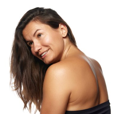 Uzun, sağlıklı saçları olan, omuzlarının üzerinden gülümseyen bir kadın. Parlak, iyi beslenmiş saçı etkili saç bakımını gösteriyor. Güzellik ve kozmetoloji kavramı, saç stili