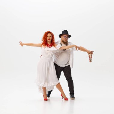 Latin dansının enerjisi. Salsa ikilisi hareketlerini ve ritmini beyazların arka planına göre mükemmelleştiriyor. Dans sınıfı kavramı, sanat, dans okulu, yetenek, klasik, modernite.