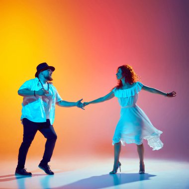 Salsa rutinine odaklanmış, enerjik dansçılar ikili antremanlar neon ışığı altında gradyan turuncu arka plana karşı kendilerini adamışlardır. Dansın romantik havası. Dans, performans, sanat, eğlence kavramı.