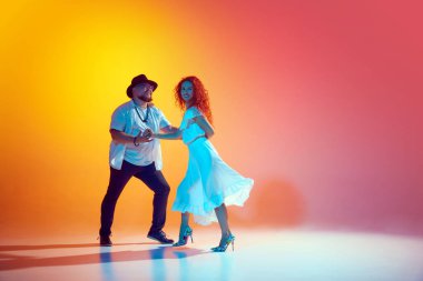 Enerji salsa sosu. Antrenman sırasında dansçılar adımlarını mükemmelleştirmek için çalışırlar ve turuncu renge karşı neon ışığı altında ritim tutarlar. Dans, performans, sanat, eğlence kavramı.