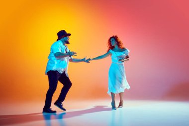 Salsa dansçıları tutkulu bir şekilde turuncu arka plana karşı tutkulu bir şekilde çalışırlar. Duygularını belli ederler. Dansın romantik havası. Dans, performans, sanat, eğlence kavramı.