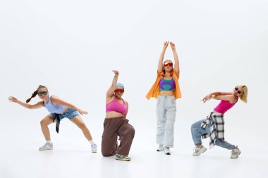 Canlı dansçı dörtlüsünün dinamik portresi, renkli sokak kıyafetleri giymesi, beyaz stüdyo geçmişine karşı enerjik bir şekilde antrenman yapması. Müzik, retro ve modernite, hareket, spor ve hobi kavramı. Ad