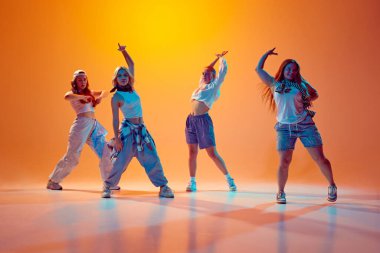 Yetenekli kızlar, serbest stilde dans eden dansçılar, eski moda kıyafetleri giymiş, neon ışıklarıyla hareket eden, gradyan arka planda dans eden. Müzik, moda ve sanat kavramı, hareket, spor ve hobi.