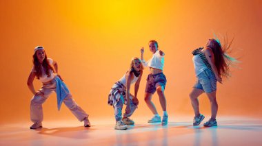 Bireysel fırlatma hareketleri. Kızlar, dansçılar dans ediyor, eski moda kıyafetlerle canlı neon ışıklarla poz veriyorlar. Stüdyonun arka planına karşı. Müzik kavramı, retro ve modernite, spor ve hobi. Ad