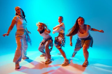 Rahat sokak kıyafetleri giymiş canlı dansçılar, canlı mavi arka plana karşı cesur pozlar verirler, enerjik ve yaratıcı bir ruh gösterirler. Müzik, sanat, retro ve modernite kavramı, hareket, hobi.