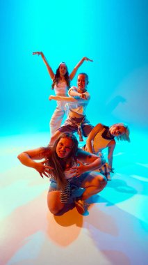 Canlı dansçılar, gündelik giysiler içinde, parlak neon ışıklarıyla gradyan stüdyonun arka planına karşı komik bir poz veriyorlar. Müzik, moda ve sanat kavramı, retro ve modernite, hareket, spor ve hobi