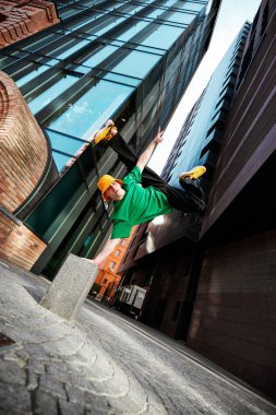 Kentsel break dans eylem sırasında yakalandı. Dansçı taklaları uygun giyimli, renkli renklerle süslenmiş, geometrik şehir manzarası çerçeveli. Yaşam tarzı kavramı, ekstrem spor, serbest stil, aktivite, hareket. Ad